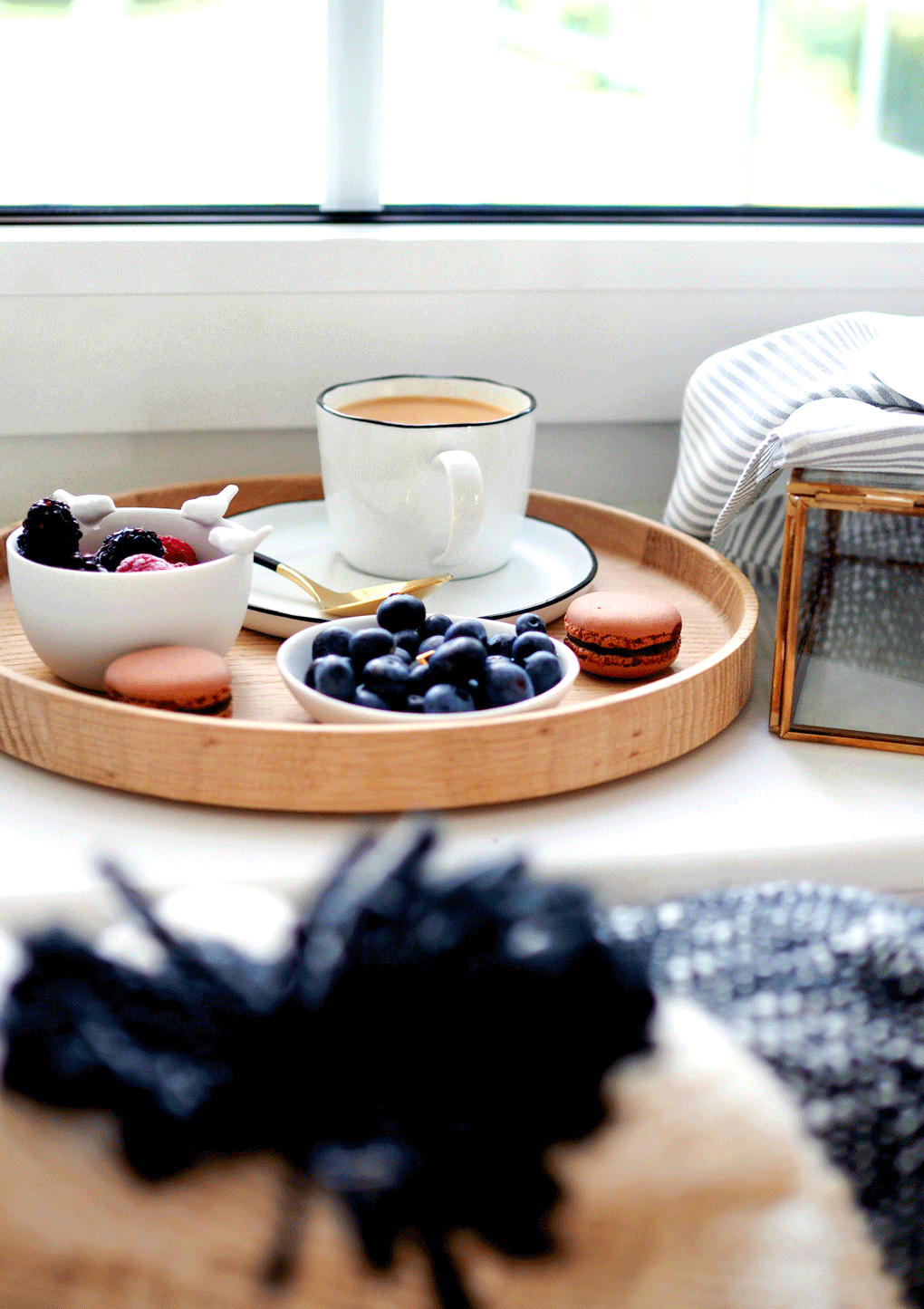 A cup of milk tea, macaroons, blueberries placed on a serving tray