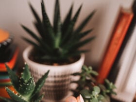 White woman wearing an orange sweater with a silver and nude manicure