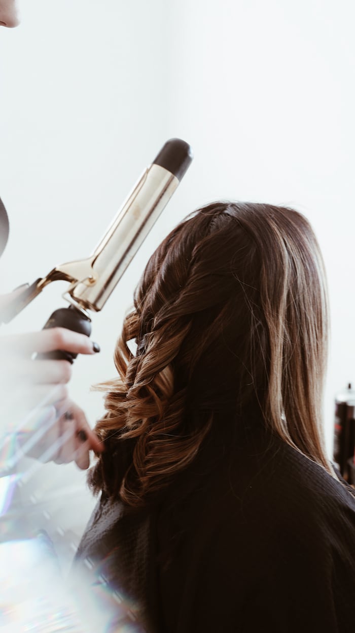 woman curling curling brunette hair with curling iron